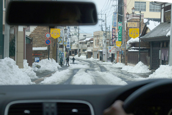 家々の角に雪の山。路面の雪は、手付かず